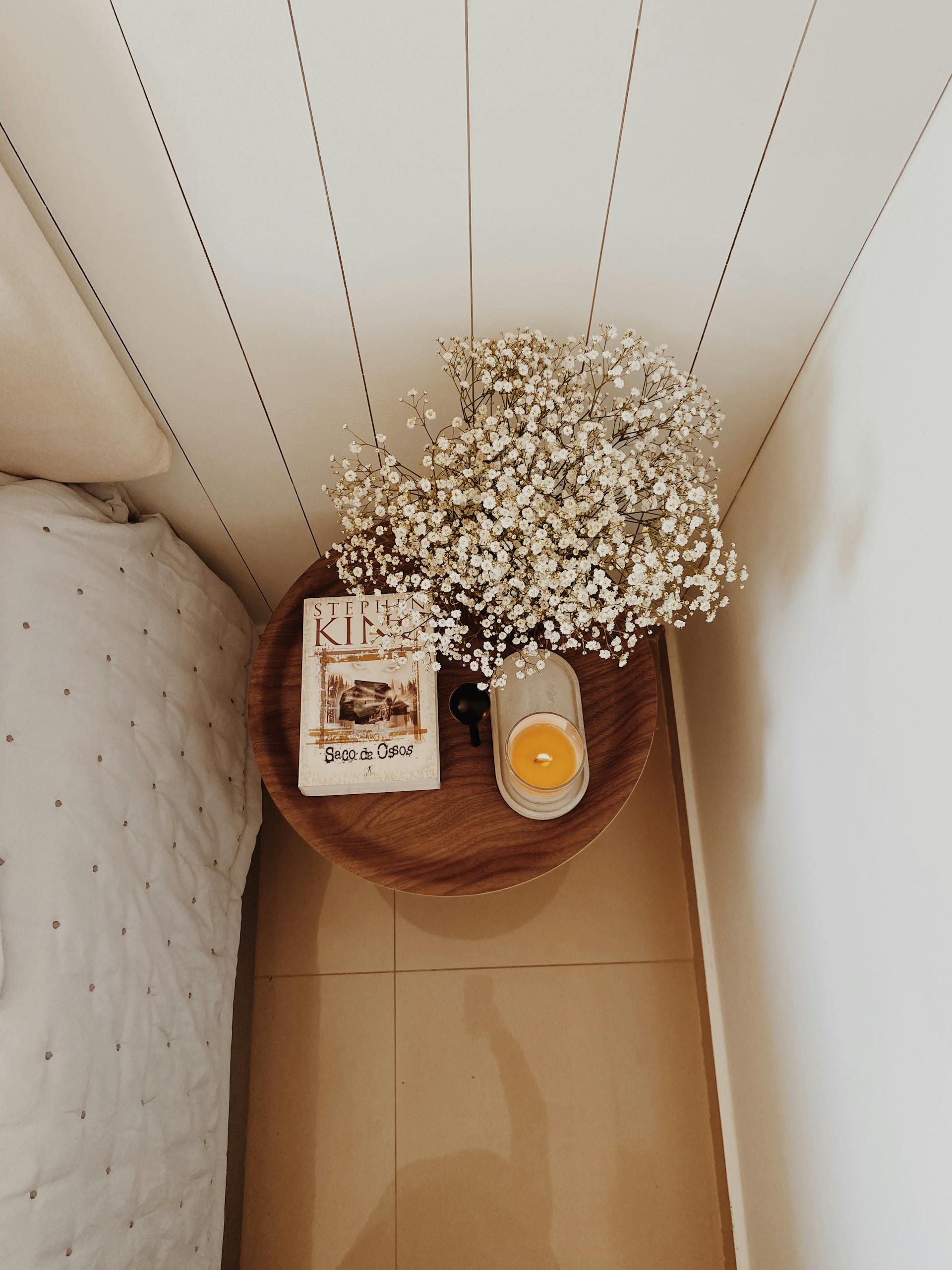 A serene bedside table setup with flowers, candle, and book in São Paulo.